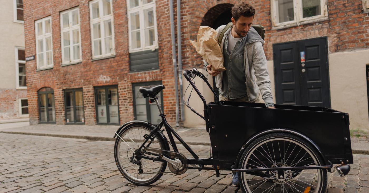 Kurier wyciągający paczki z roweru cargo