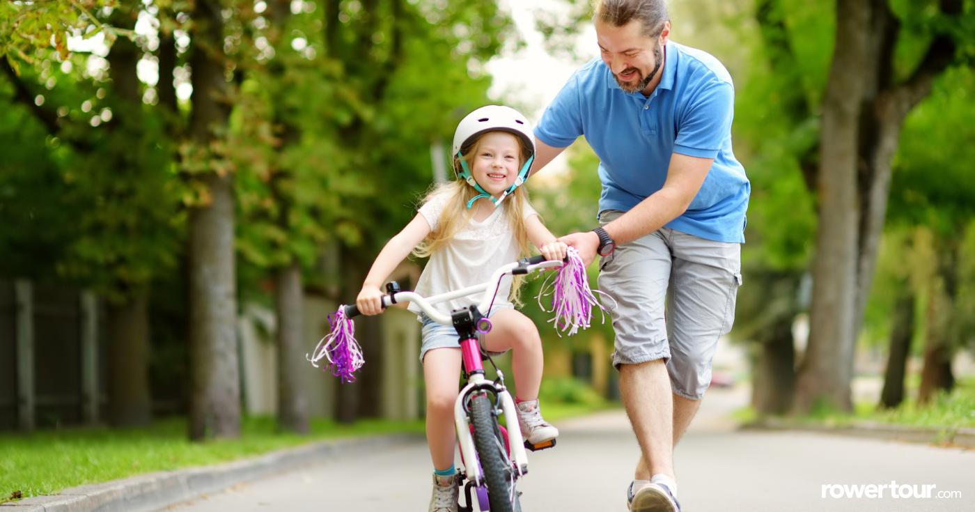 Dziecko uczące się jeździć na rowerze z tatą